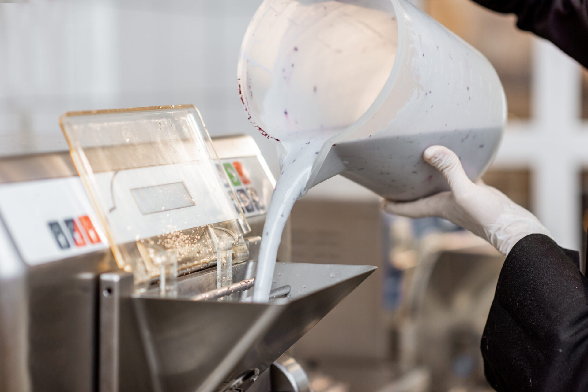 Chef pouring mixed milk base into the ice cream machine or freezer, close-up