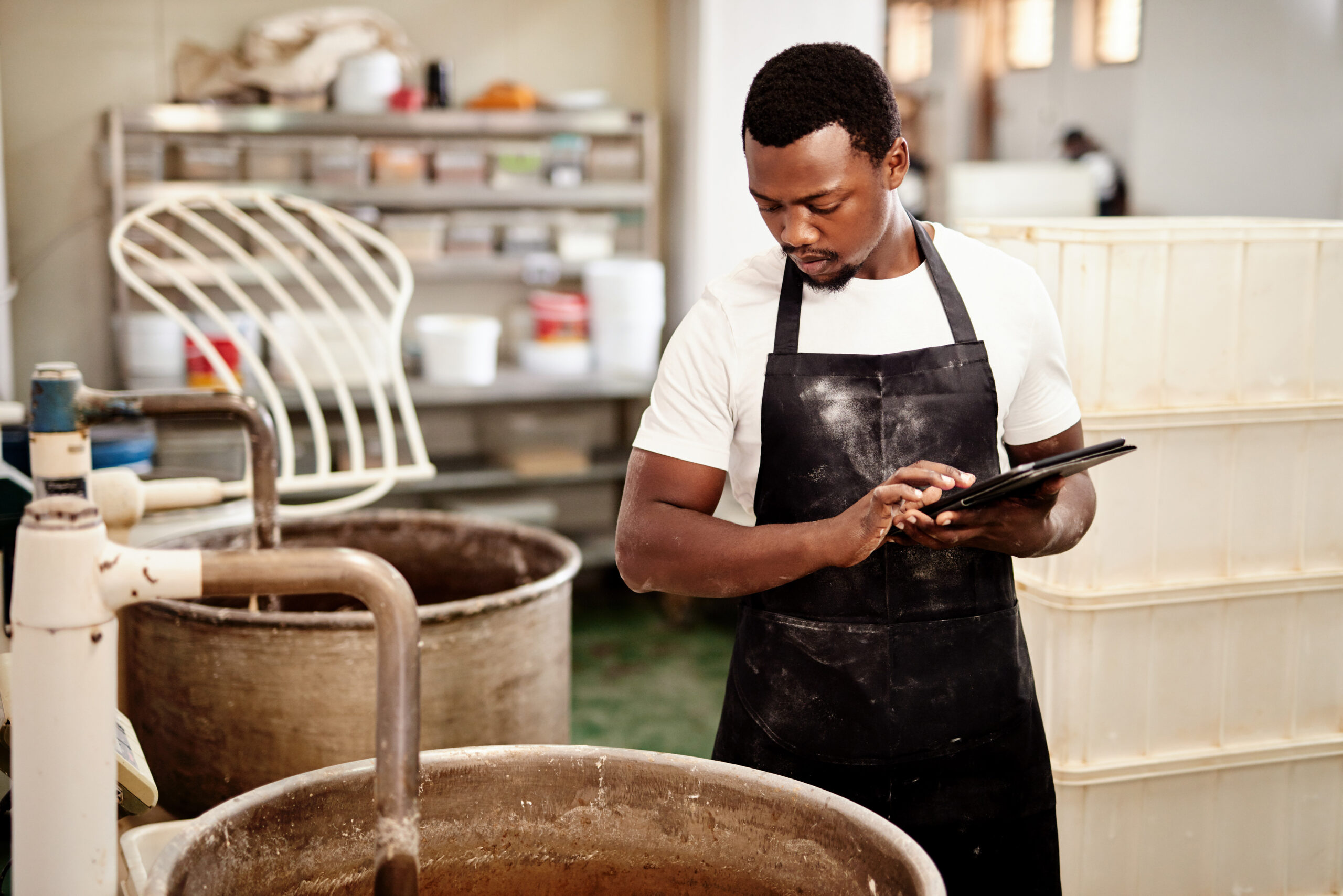 Cropped shot of a man using a digital tablet while working in a bakery.