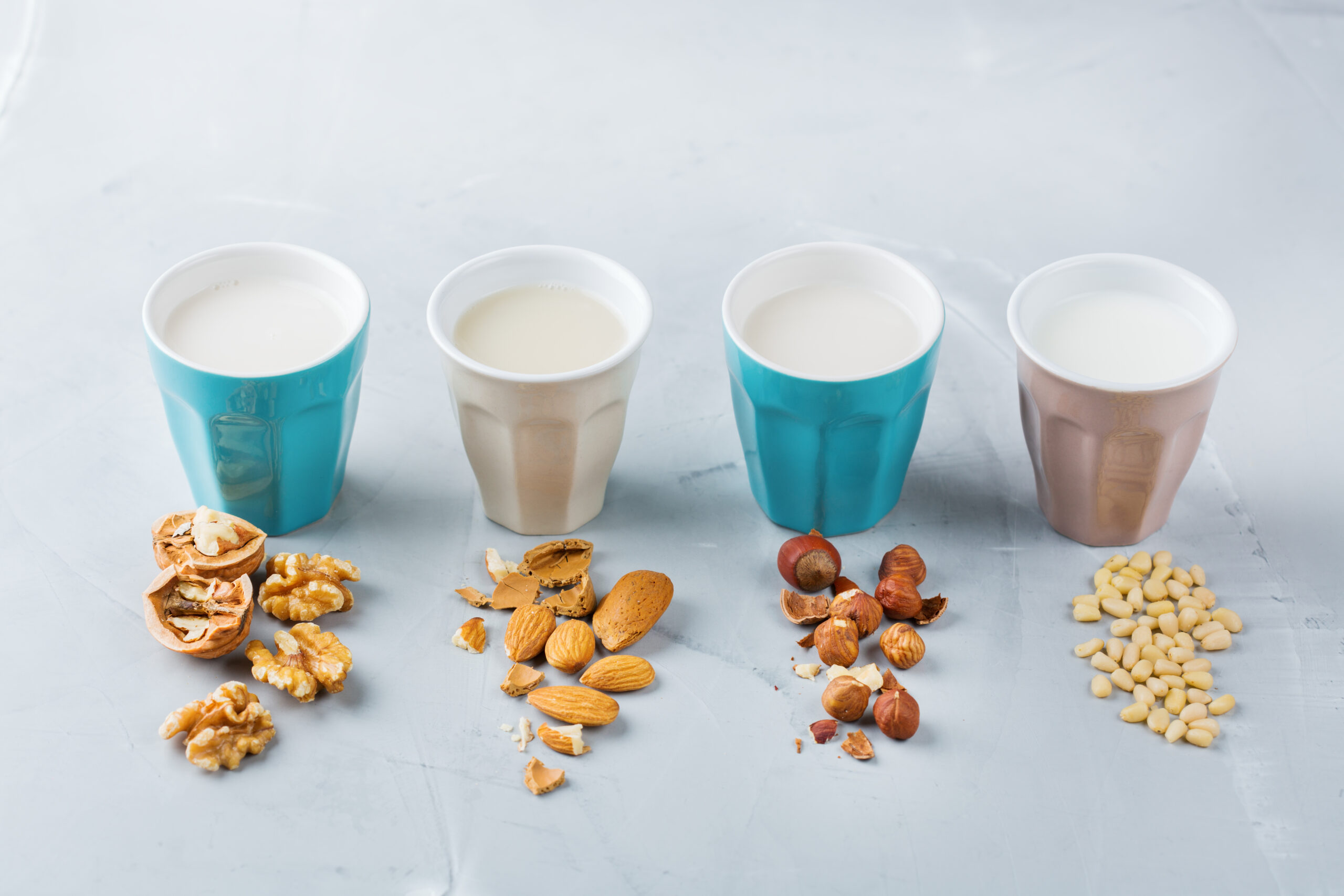 Food and drink, health care, diet and nutrition concept. Assortment of organic vegan non dairy milk from nuts in glasses on a kitchen table